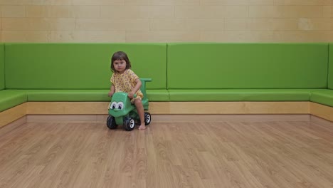 Niño-Feliz-Montando-Un-Coche-De-Juguete-En-El-Interior