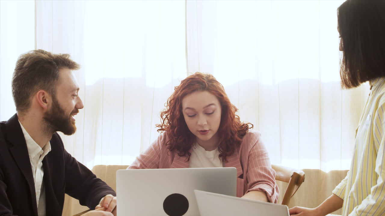 группа из трех многонациональных коллег, сидящих за столом и обсуждающих работу во время собрания коллектива 2