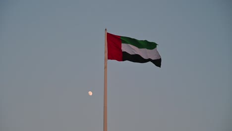 bandeira dos emirados árabes unidos acenando no ar lua crescente no fundo, o símbolo nacional dos emirados árabes unidos, dia nacional dos emirados árabes unidos 2020, vídeo 4k