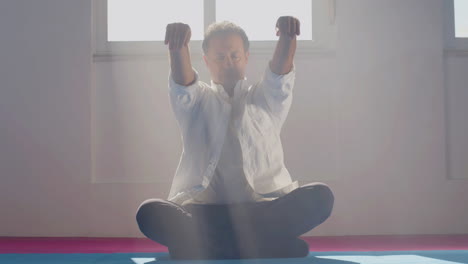 Man-moving-hands-while-sitting-in-lotus-position-on-floor