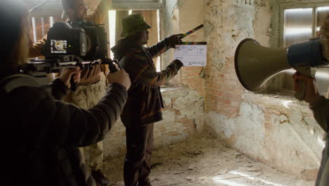 equipo de producción y camarógrafo grabando la escena de una niña tratando de escapar por la ventana de un edificio en ruinas