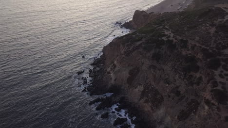 Sunset-Golden-Hour-with-purple-light-above-Pacific-Ocean-Coastline-in-Malibu,-California,-Aerial-Wide-Angle-Establishing-Shot