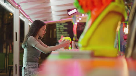 woman with beer sits at bar counter. thoughtful lady with ordered drink spends free evening in local pub. lonely brunette guest enjoys alcoholic beverage