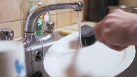 Scrubbing-dishes-clean-with-brush-in-the-kitchen-sink