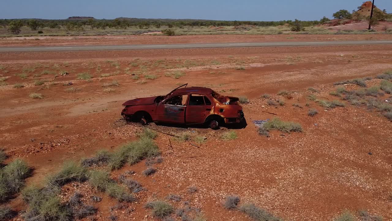 dando vueltas alrededor de un coche quemado, oxidado y abandonado junto a la carretera en el interior de australia