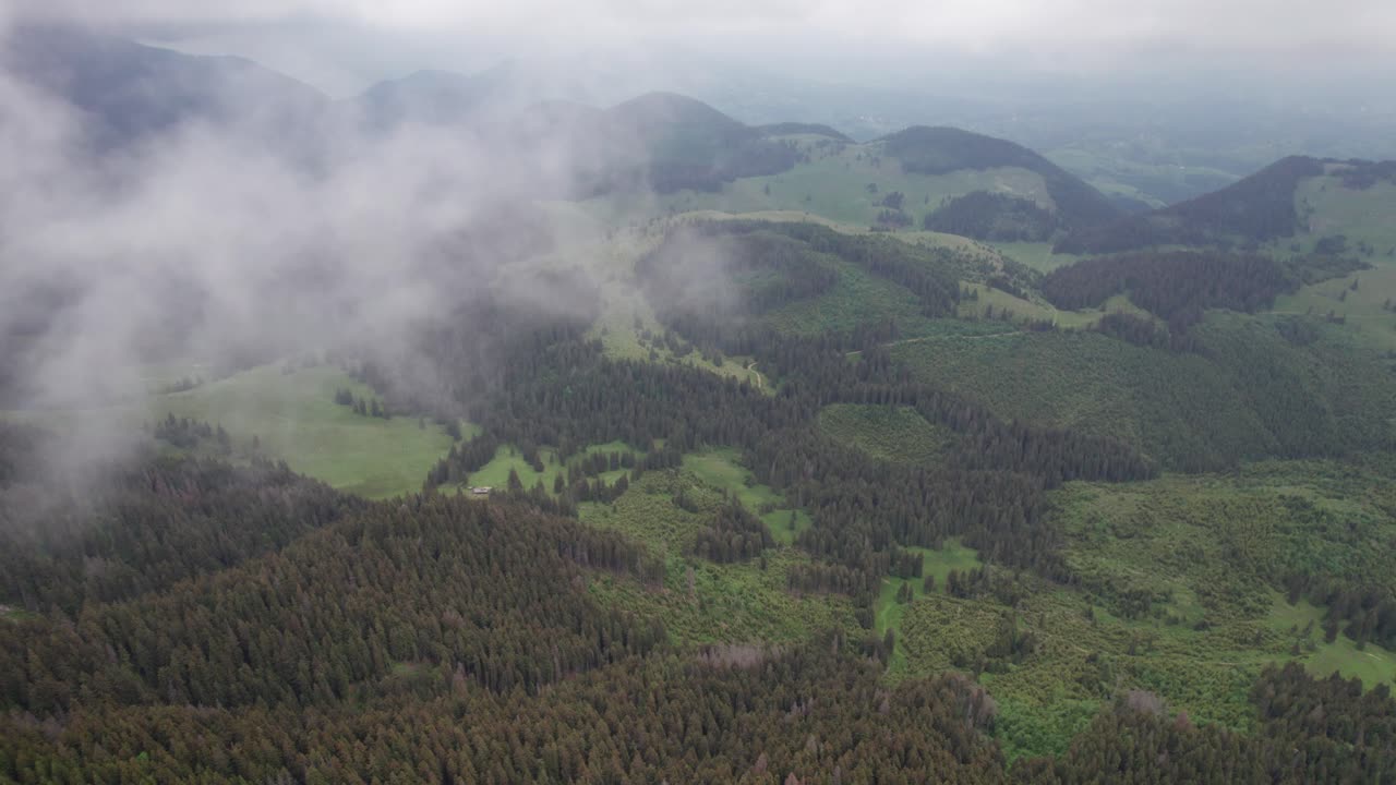paisaje montañoso nebuloso con denso bosque y nubes a gran altitud, paisaje verde y natural, vista aérea
