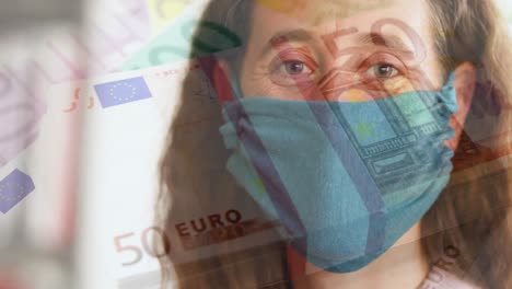 Digital-composite-video-of-stack-of-Euro-bills-against-woman-wearing-face-mask-in-background