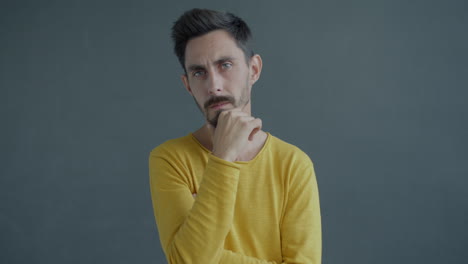 man in a yellow shirt, pensive expression