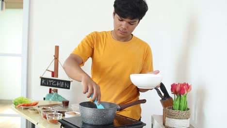 young man cooking noodles in a kitchen