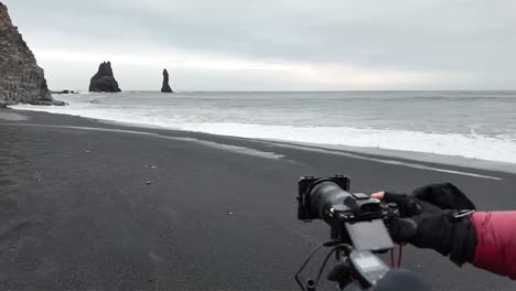 a video of iceland's black sand beach shows dramatic waves crashing against the shore, with dark volcanic sand contrasting against the frothy white water and rugged cliffs.