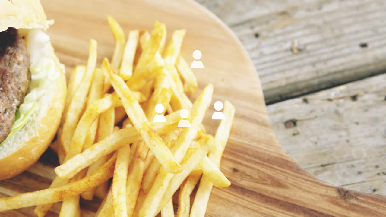 Burger and fries on wooden board with people icons overlay animation