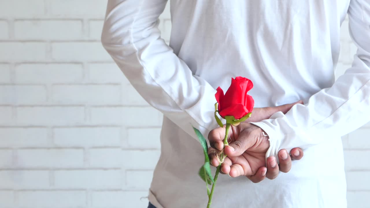 hombre escondiendo una rosa roja detrás de su espalda