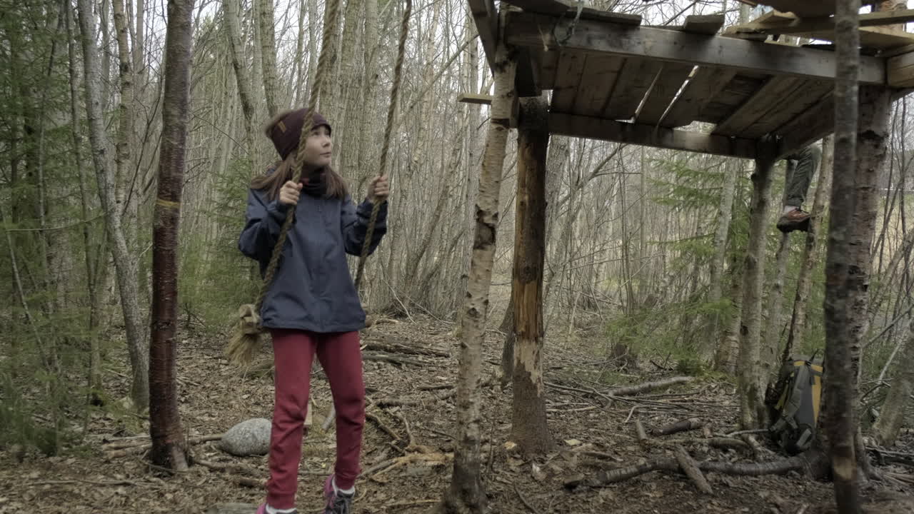 A girl with brown hair swinging in the woods