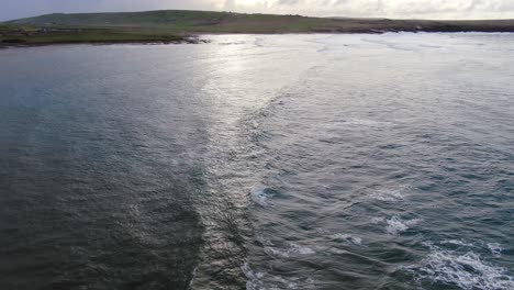 vista aérea en cámara lenta de las olas del mar del norte mientras vuela lejos del sol