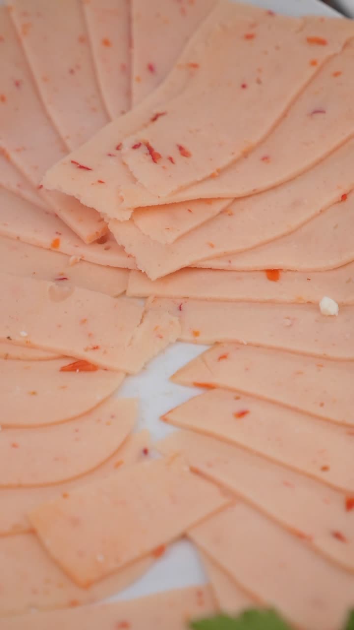 Salumi affettati sottilmente con peperoni rossi su un piatto bianco