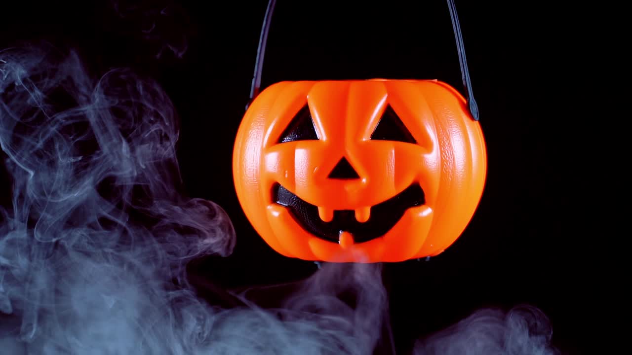 concepto de halloween - moviendo linterna de calabaza de plástico con humo blanco alrededor aislado en fondo negro oscuro, aterrador y estado de ánimo de horror.