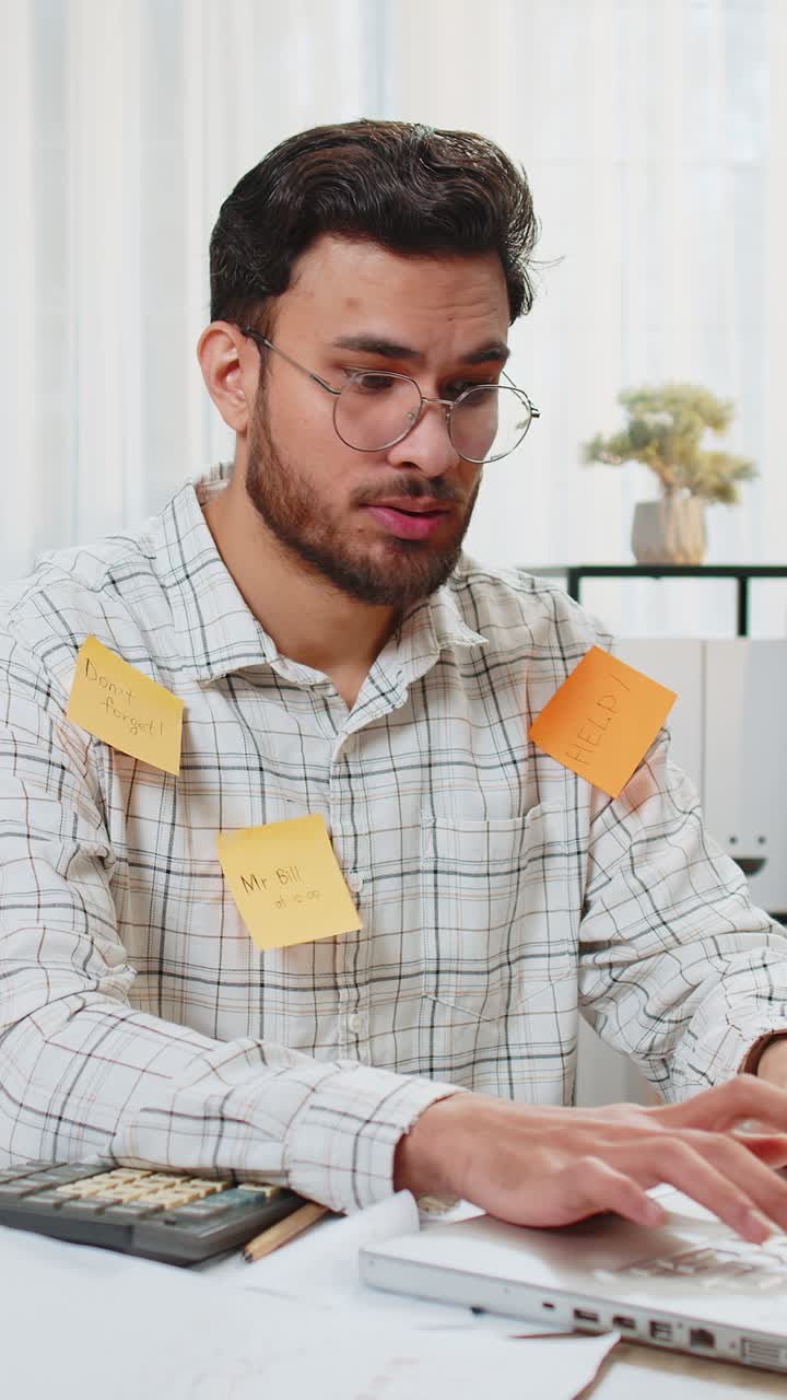 Indian businessman work on laptop sticky notes with many tasks inscription overworked at office