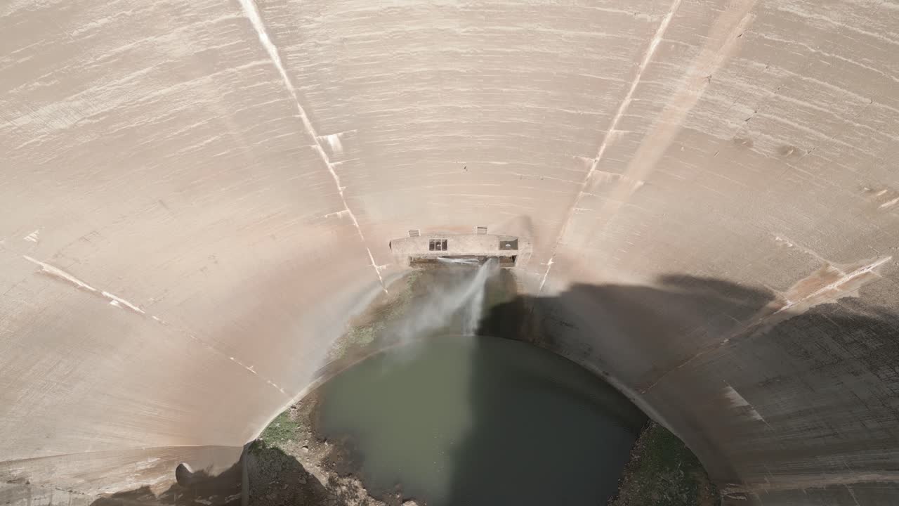 Aerial view tilt down of old huge dam with water leakage