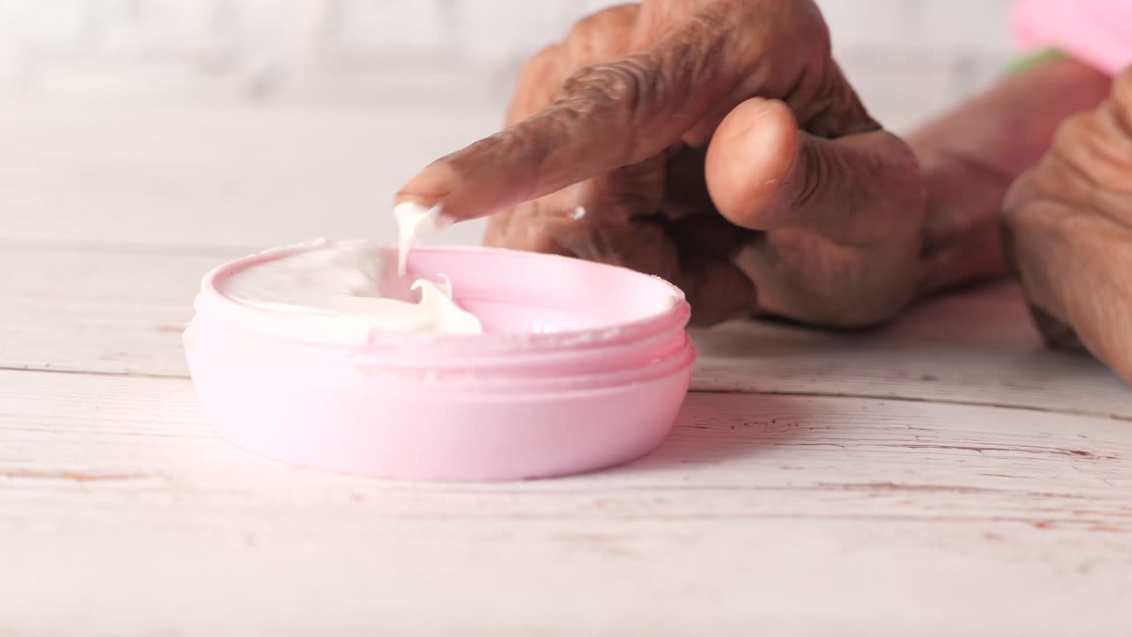 Oudere vrouw die handcrème aanbrengt
