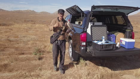 man doing falconry training with falcon gets gear equipment from truck