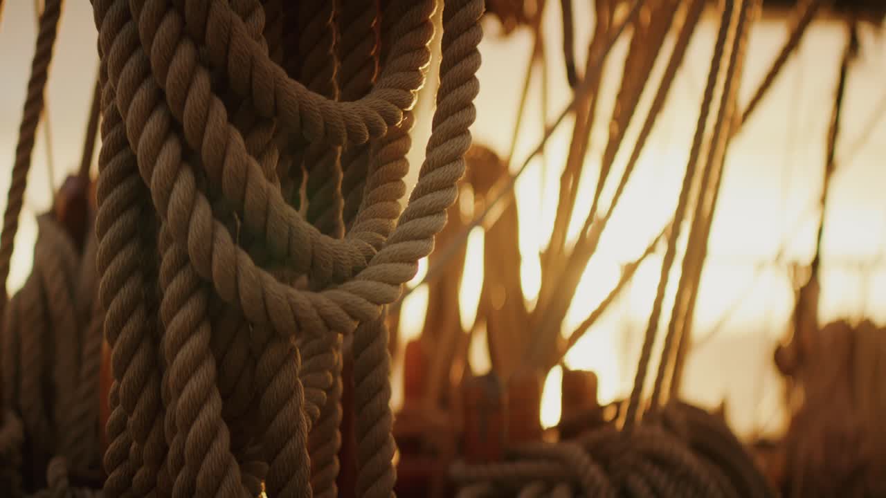 Sunrise shining through sailing ship rigging on traditional tall ship at sea