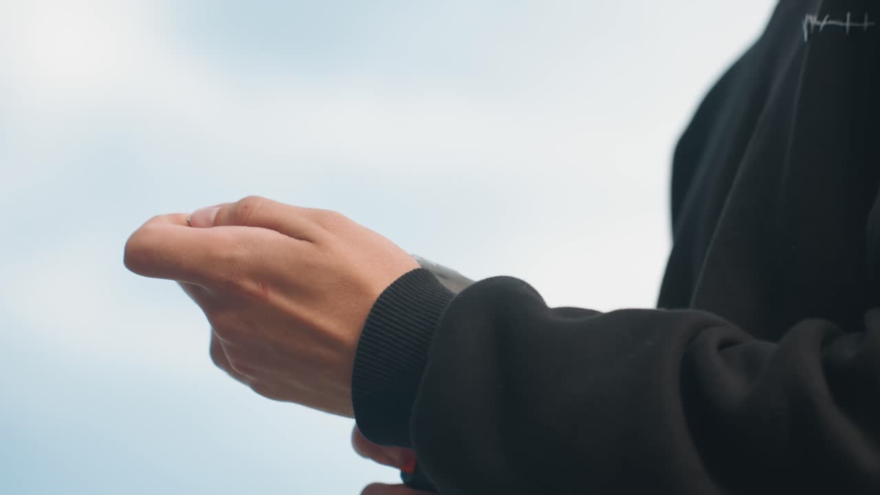 準備中、コードレスドリルをしっかりと持ち、空を背景にした人物の手元のクローズアップ。電動ドリルを慎重に握る様子。手に工具を持つ。