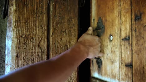 Slow-motion,-anonymous-man's-hands-opening-rustic-outdoor-cabin-wooden-door