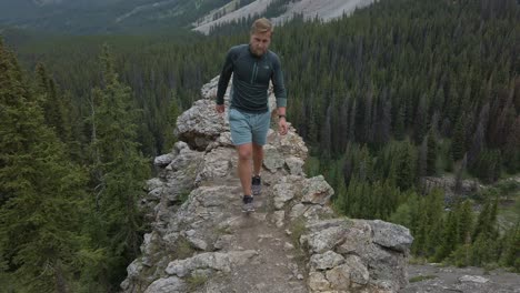 Hiker-stepping-of-ledge-eye-contact-Rockies-Kananaskis-Alberta-Canada