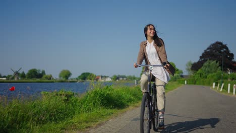 Young-carefree-woman-cycling-next-to-Dutch-water-canal