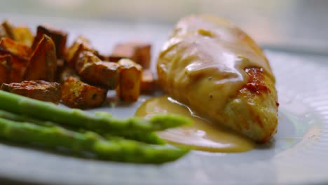 elegant dish of pan fried chicken fillet with asparagus and parmentier potatoes with creamy peppercorn sauce. high quality cooked restaurant food.