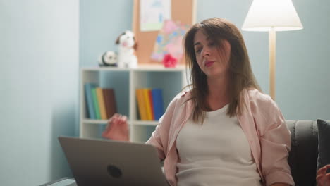 mujer con portátil ajusta el cabello trabajando en línea desde casa