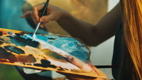 mujer mezclando a mano pinturas al óleo en una paleta de madera. artista creativo pintando una imagen