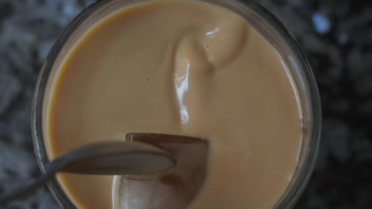 Primo piano dall'alto di caffè freddo con latte e due cubetti di ghiaccio in un bicchiere