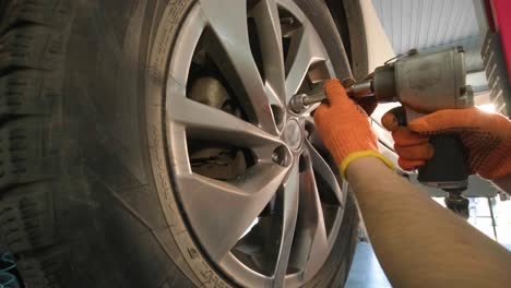 hands of mechanic with tool, changing tyre of car at auto service