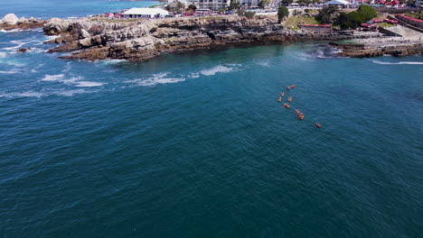 drone pullback tilt up over kayakers in walker bay - hermanus ecotourism