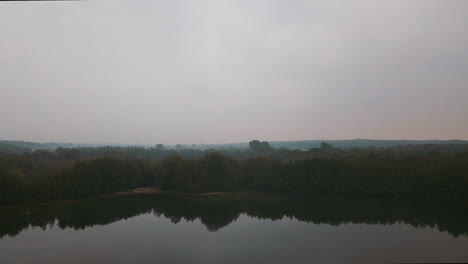 a beautiful lake in the middle of a forest on a foggy morning