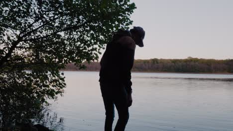 Young-Tall-Guy-Walks-to-The-Gyllebo-Lake,-Touches-The-Water-and-Exhales-and-Walks-Away,-Österlen,-Sweden---Tracking-Medium-to-Wide-Shot