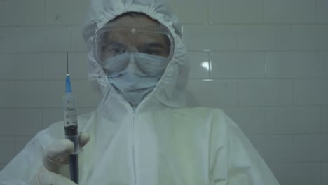 medical doctor wearing protective ppe spilling out medicine off a syringe after filling it with covid 19 vaccine