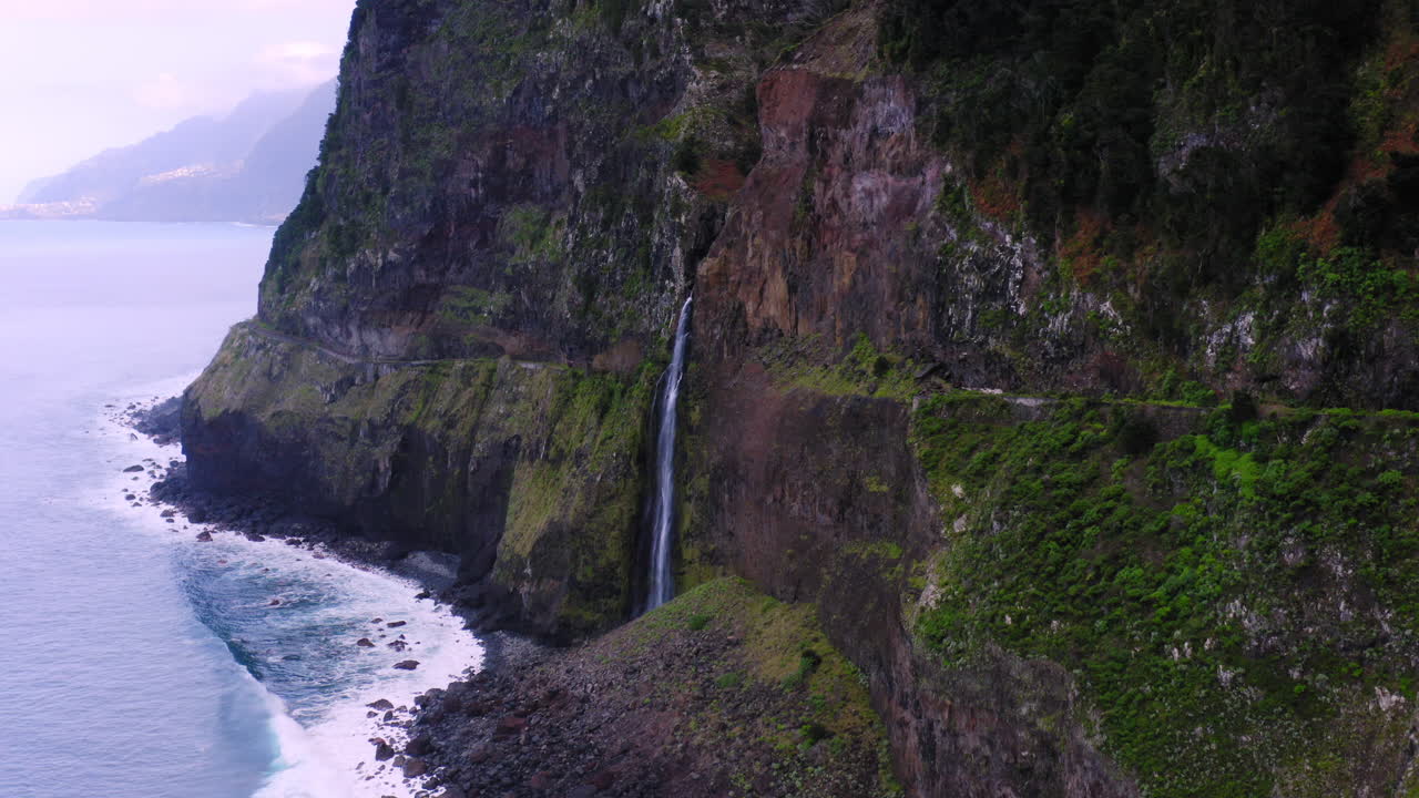cascada de madeira en las montañas y el océano azul como telón de fondo durante el día soleado en la isla, portugal, antena hacia el vuelo