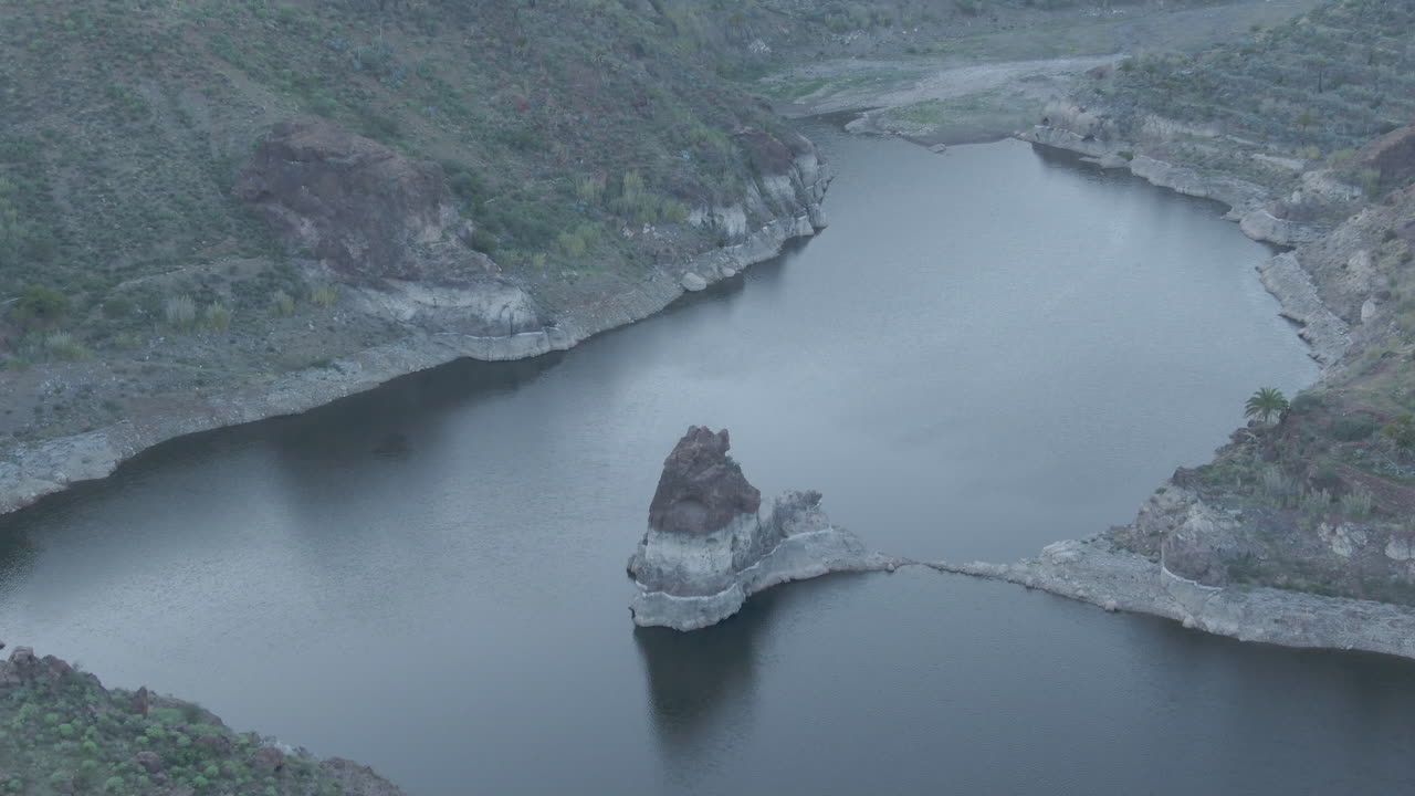 Sorrueda dam, Gran Canaria: aerial view over the famous dam and flying over one of the rock formations and with completely calm water