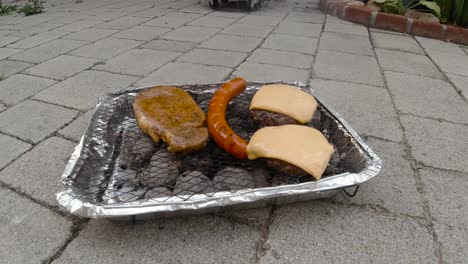 vista bloqueada de la mini parrilla de barbacoa desechable con diferentes y hamburguesas con queso en el suelo de baldosas