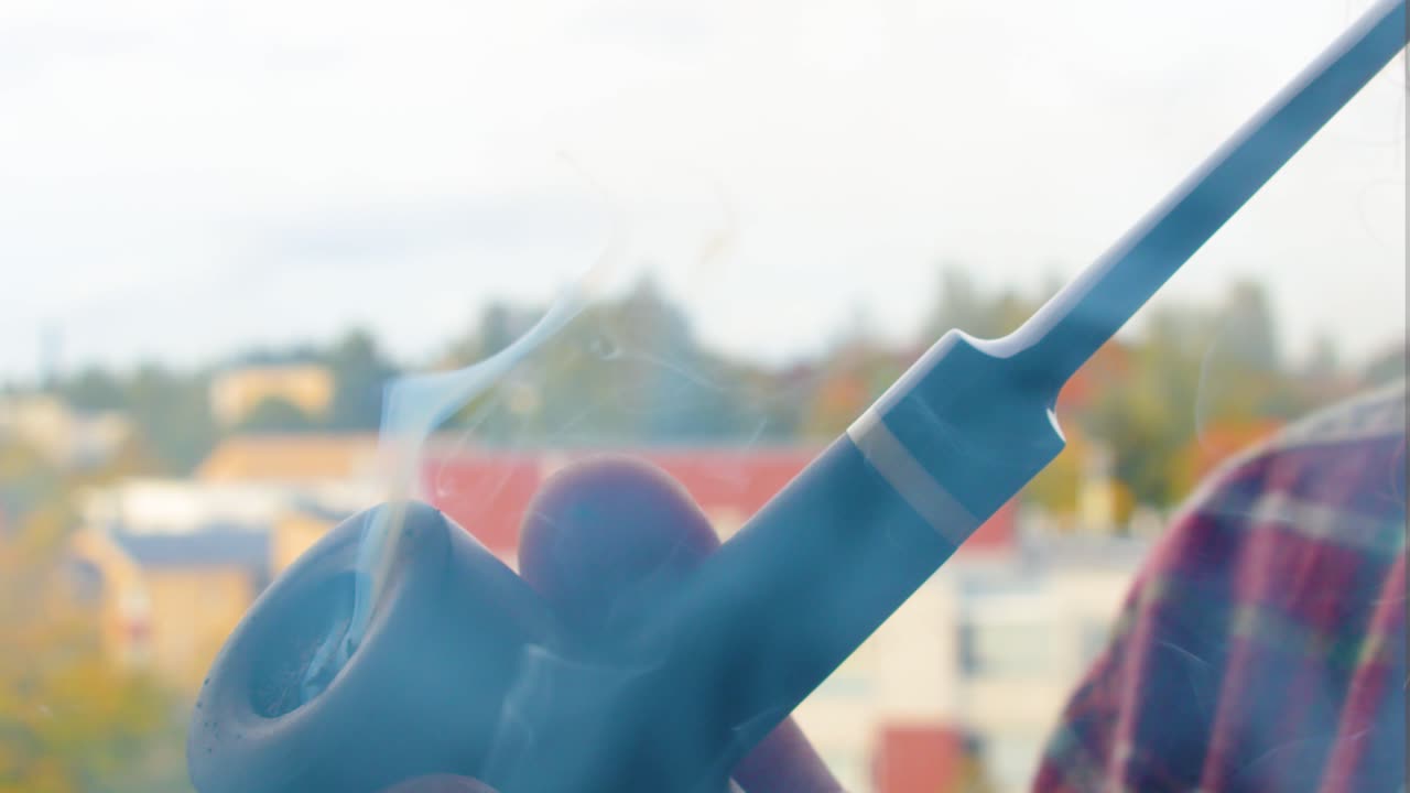 고품질의 담배로 가득 찬 파이프를 통해 밖에서 담배를 피우고, 진저 수염을 가진 남자가 은 셔츠를 입고 증기를 내쉬고, 파이프에 초점을 맞춘 근접 장면