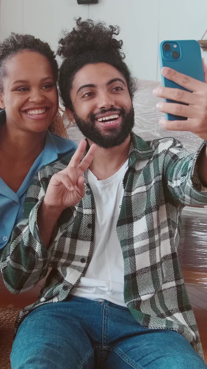 Giovane famiglia felice, composta da donna e uomo, si scatta un selfie insieme con il telefono dopo il trasloco.
