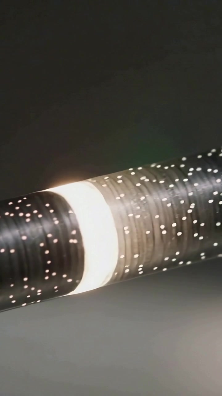 Video verticale: Attivazione di una banda luminosa anulare che scorre lungo un tubo punteggiato in studio, rivelando anelli.