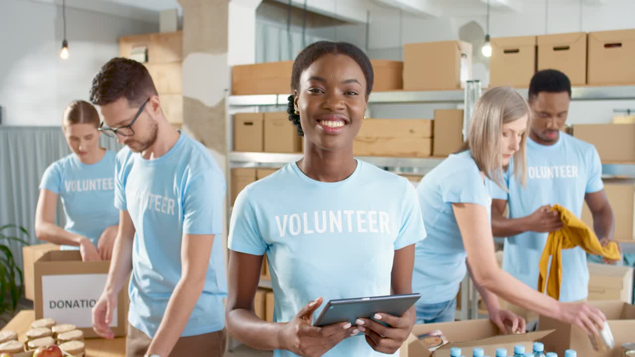 African american female volunteer typing on tablet and smiling at camera
