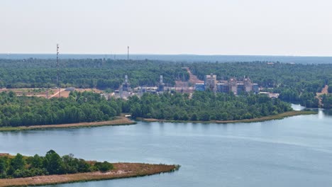 Er-Bewegt-Sich-Langsam-Nach-Links-über-Einer-Kleinen-Halbinsel-Und-Einer-Großen-Seebucht,-Hinter-Der-Sich-Ein-Kraftwerk-Befindet