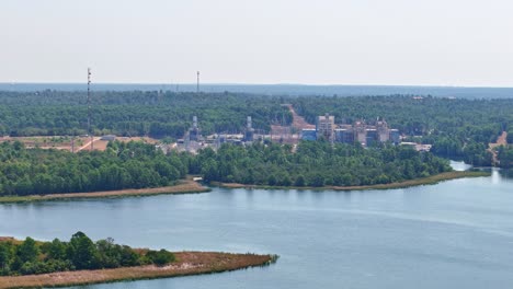 moviéndose lentamente a la izquierda por encima de una pequeña península y una gran entrada de lago que tiene una planta de energía detrás de ella