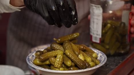 chef puts pickles into white plate