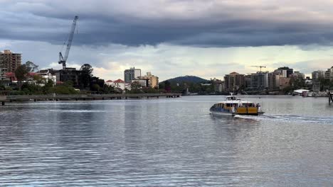 thick layer of ominous clouds sweeping across the sky with citycat ferry cruising on brisbane river with residential buildings along the river, severe weather forecasted, brisbane city, queensland