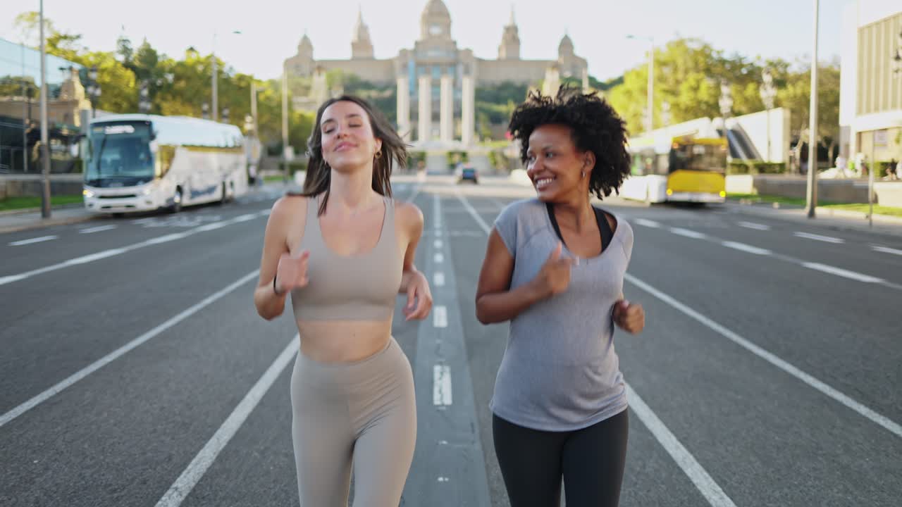 Due donne felici che fanno jogging insieme su una strada cittadina
